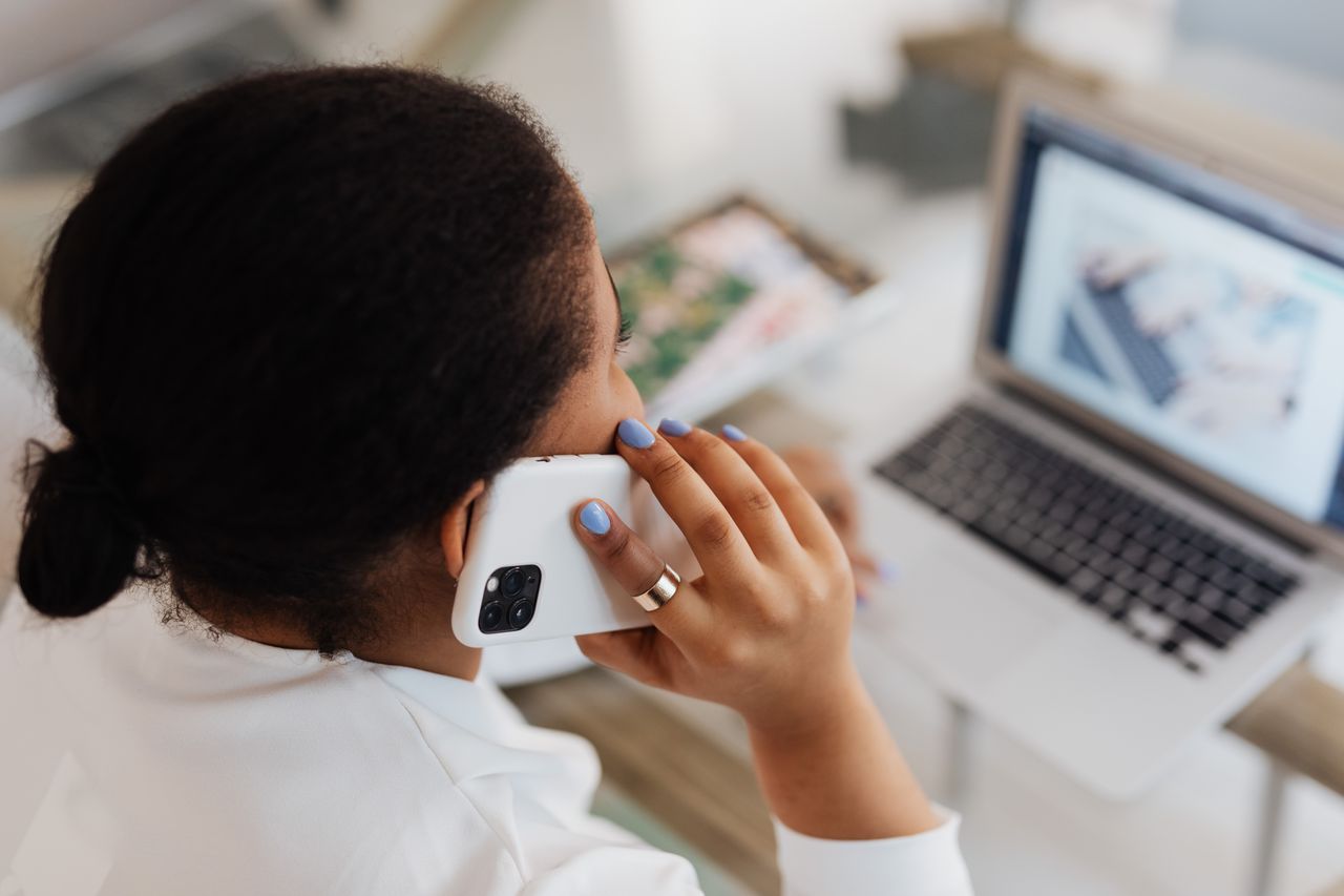 Une femme transfère les photos de son iPhone vers un ordinateur portable depuis son bureau à domicile