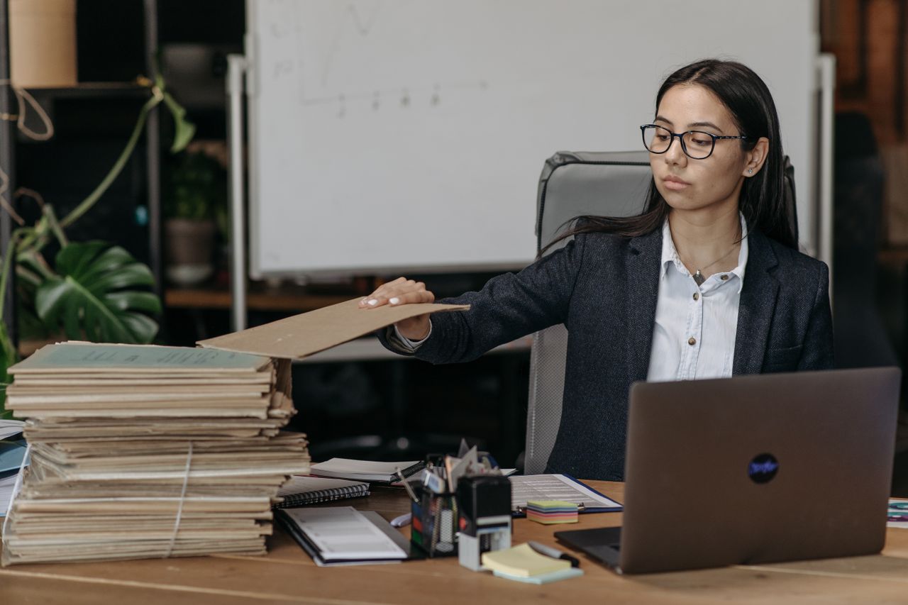 Une personne transfère des dossiers depuis un ordinateur portable vers un nouveau cloud, dans un bureau